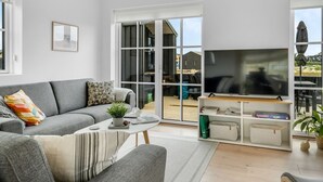 Un salon moderne avec un canapé gris, une table basse et un téléviseur posé sur un meuble en bois.