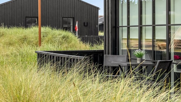 Un bâtiment moderne doté d’une grande fenêtre, d’une clôture en métal et d’un espace verdoyant.