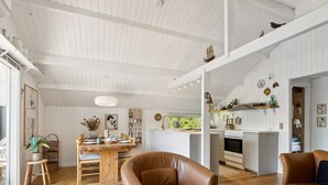 Amplia sala de estar con piso de madera, un sofá de cuero marrón y una mesa de comedor para cuatro.