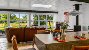 Ein moderner Essbereich mit Tisch für zwei Personen, einer Couch und Blick auf Grünfläche draußen.
