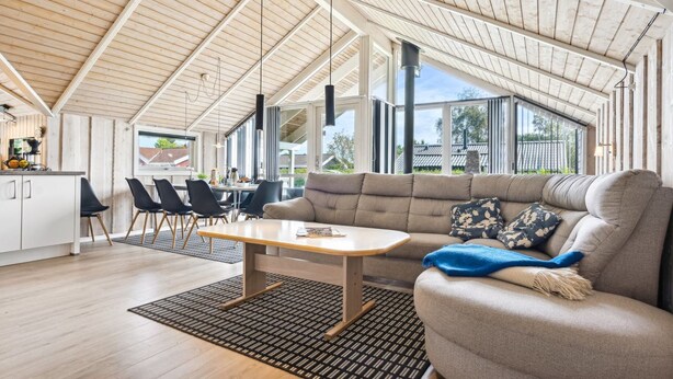 Amplia sala de estar con techo alto, un sofá, una mesa de centro y un comedor con sillas y una mesa.