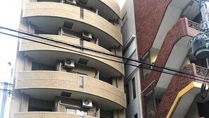 Un edificio a più piani con una facciata curva, numerosi balconi e un ingresso a livello strada con una porta ben visibile.