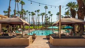 A pool area with lounge chairs, umbrellas, and palm trees. - Luxury Palm Valley 3BR  3 bath condo (Palm Desert)