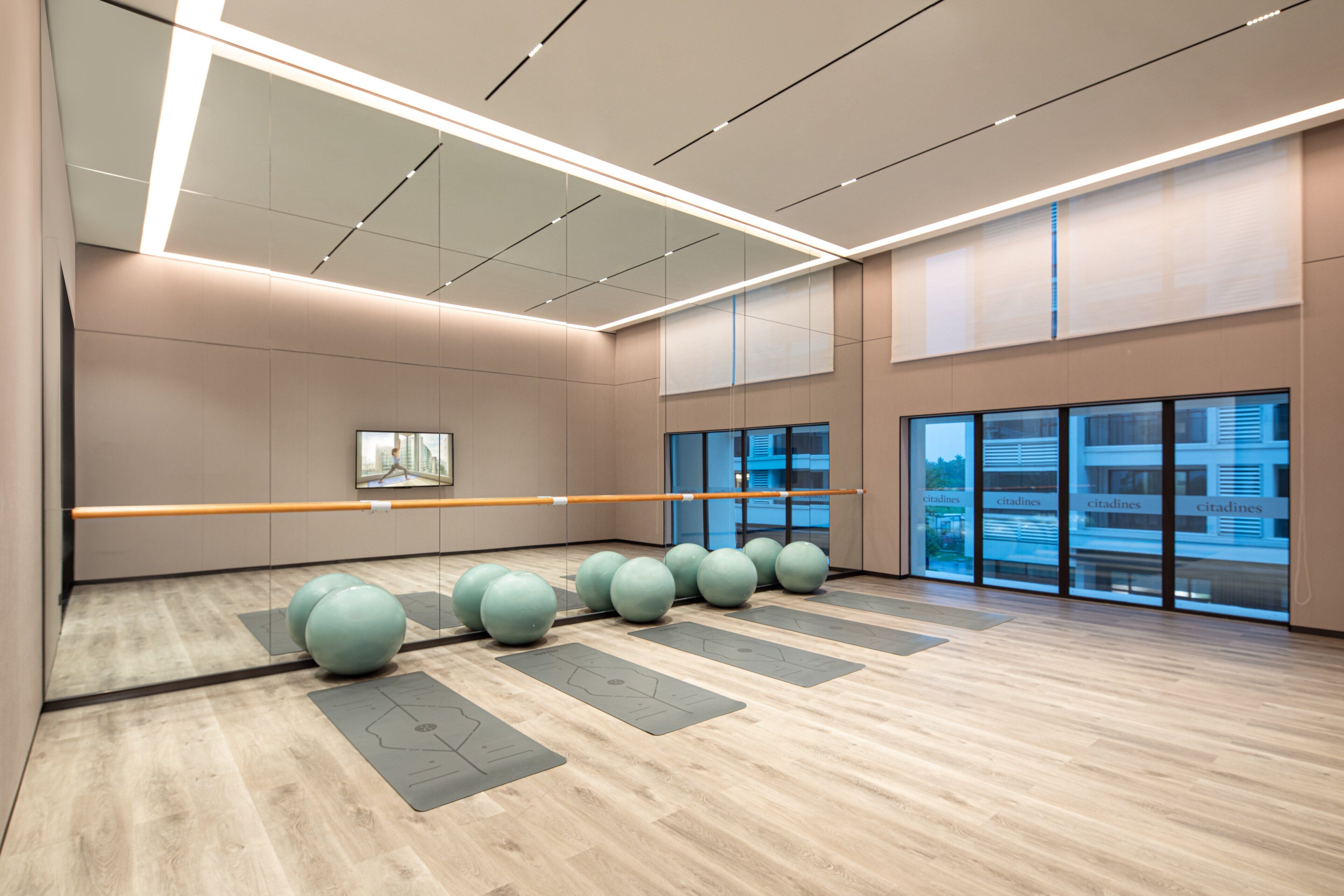 A spacious room with a wooden floor, exercise balls, and a ballet barre.