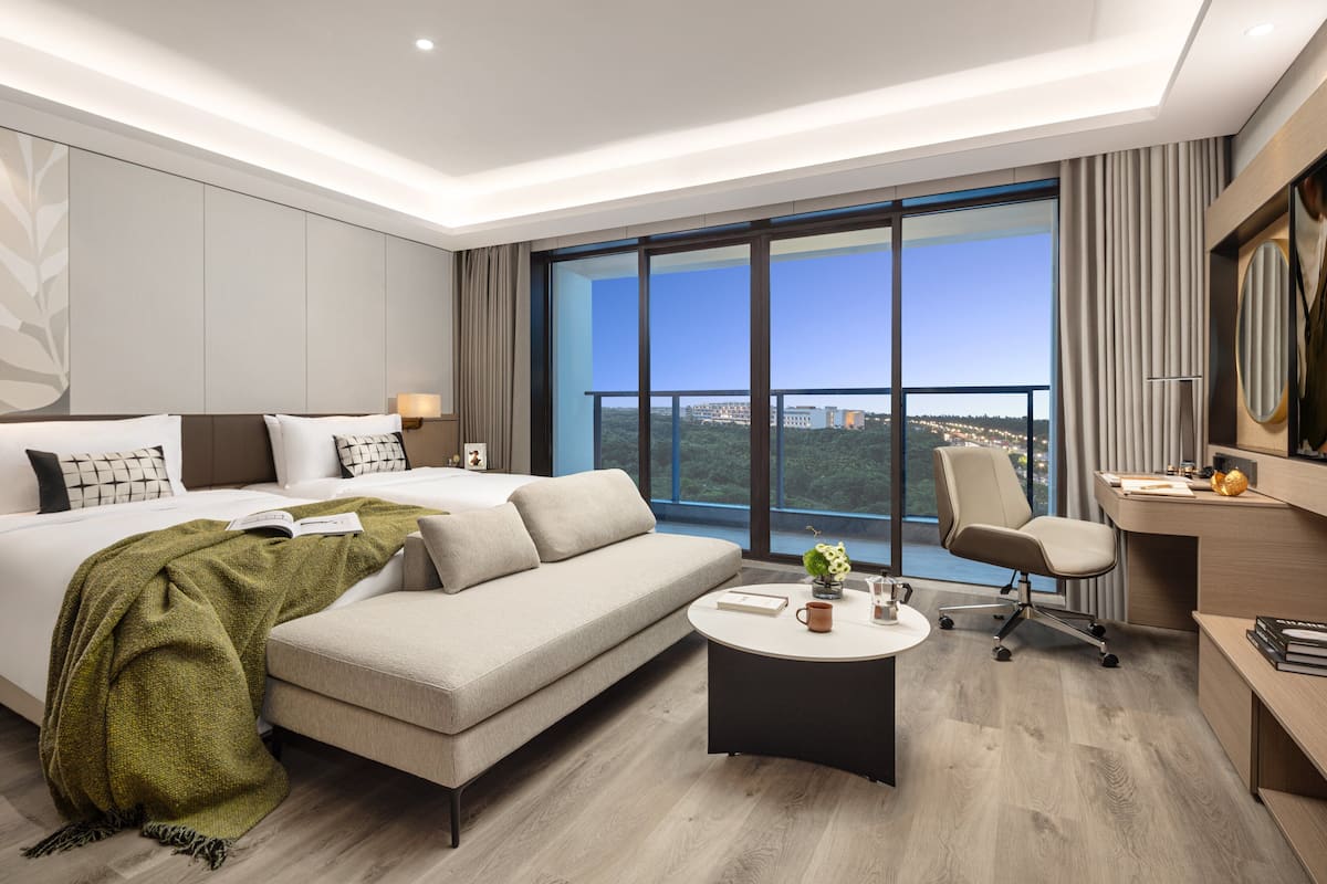 Een moderne hotelkamer met een groot bed, een bank, een bureau en uitzicht op de stad.
