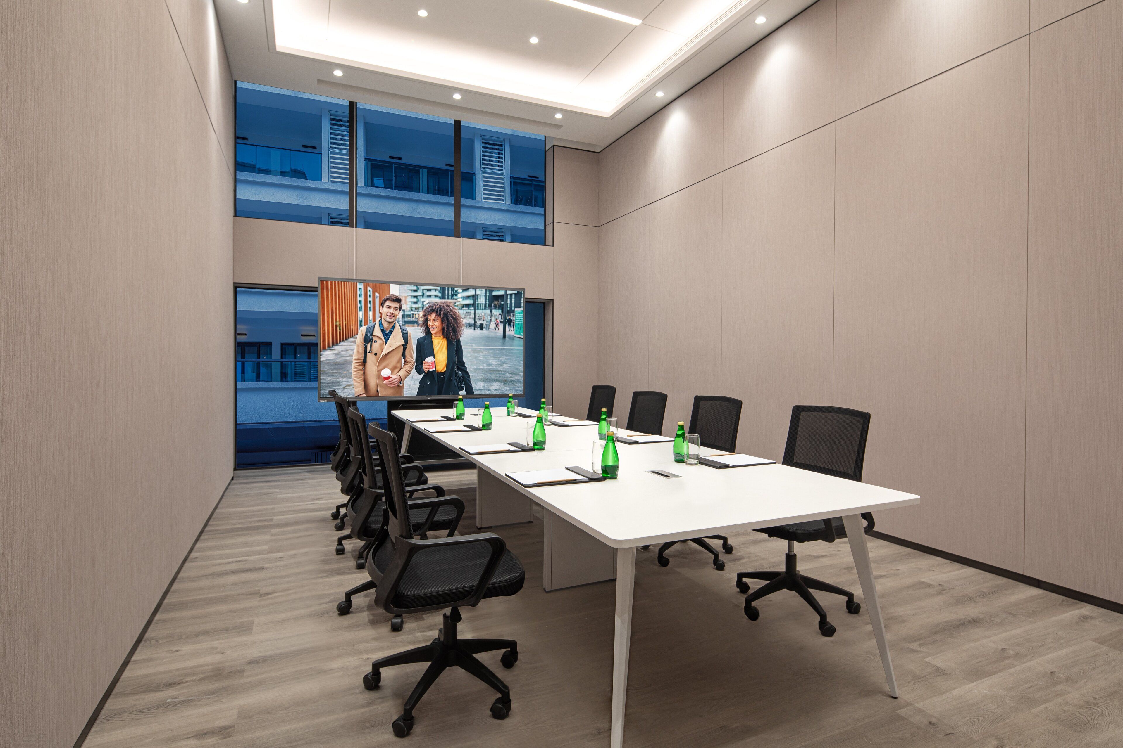Une salle de conférence avec une longue table, des chaises et une grande affiche accrochée au mur.