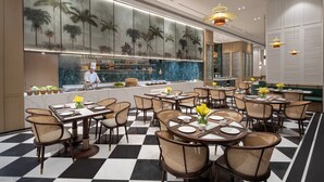 A restaurant with a checkered floor, tables with chairs, a bar area, and a large wall with palm tree artwork. - Citadines Hope City Boao (Qionghai)