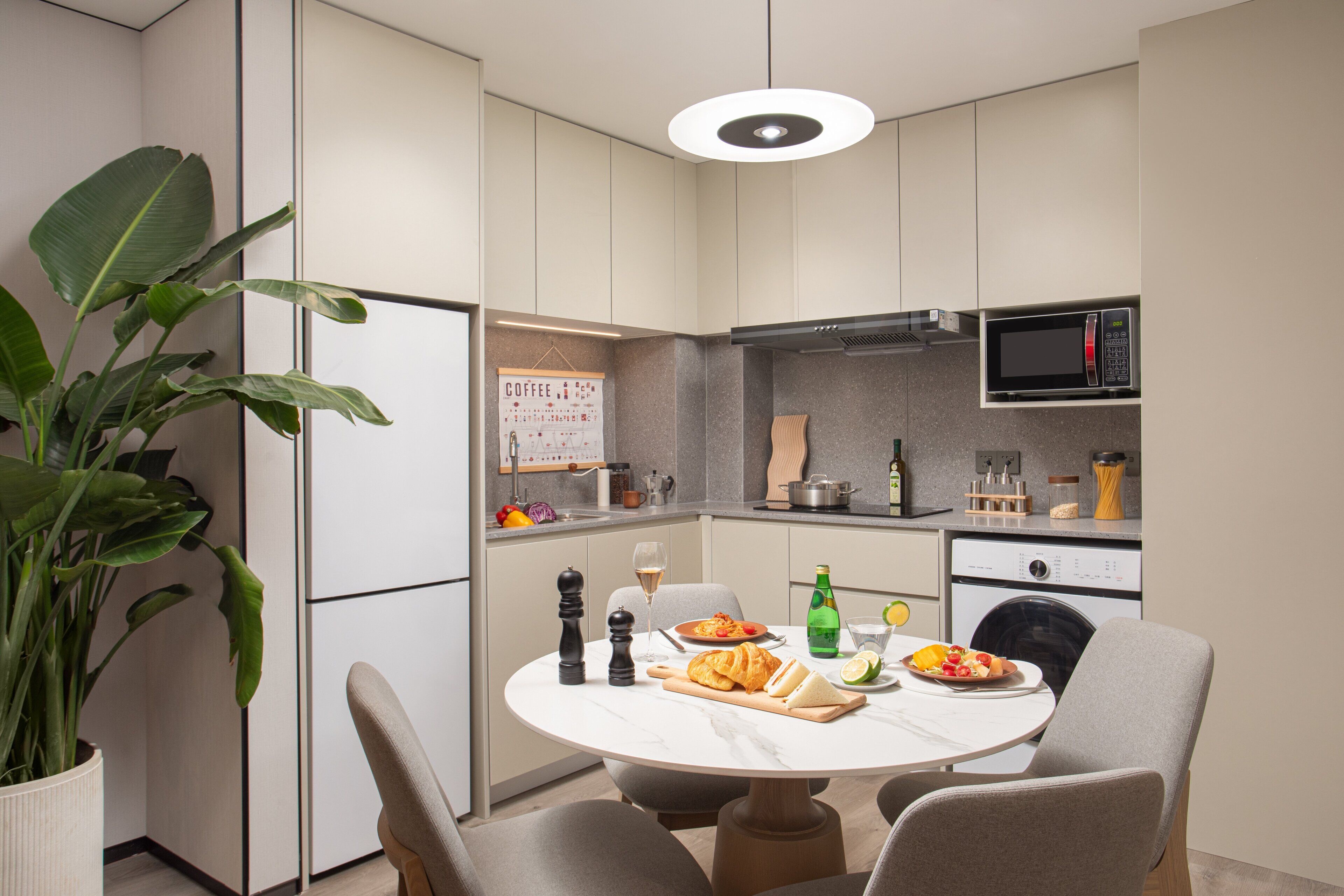 A modern kitchen with a dining table, chairs, a potted plant, and various kitchen appliances.