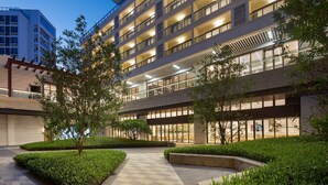 A modern hotel with multiple floors, large windows, and a well-maintained outdoor area with pathways and greenery. - Citadines Hope City Boao (Qionghai)