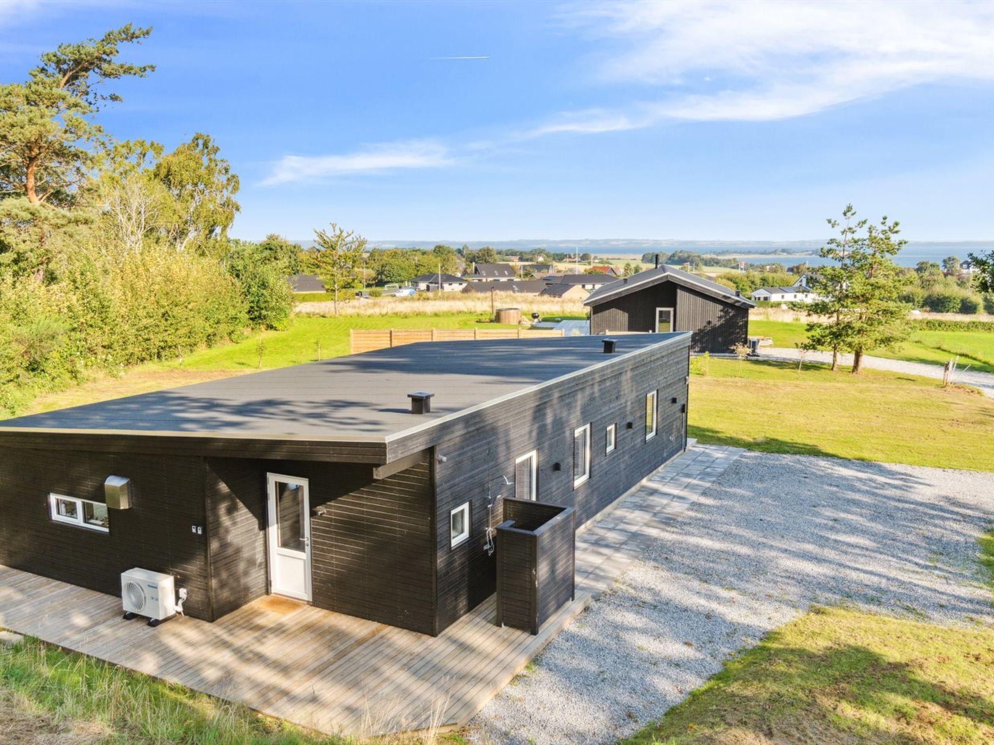 A modern building with a flat roof, large windows, and a gravel driveway.