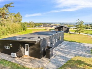 Un bâtiment moderne doté d’un toit plat, de grandes fenêtres et d’une allée gravillonnée.