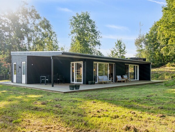 Une maison moderne dotée d’un patio couvert, de portes-fenêtres coulissantes et d’une terrasse.