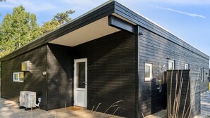 A modern, dark wooden cabin with a covered porch, a small window, and a door. - "Uma" - 1.5km from the sea by Interhome (Knebel)