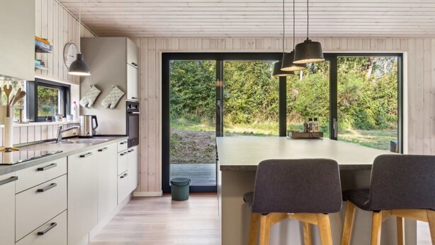A modern kitchen with wooden cabinets, a large window, and a dining area with two chairs. - "Uma" - 1.5km from the sea by Interhome (Knebel)