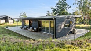 A modern house with a deck, large sliding glass doors, and a small outdoor seating area. - "Uma" - 1.5km from the sea by Interhome (Knebel)