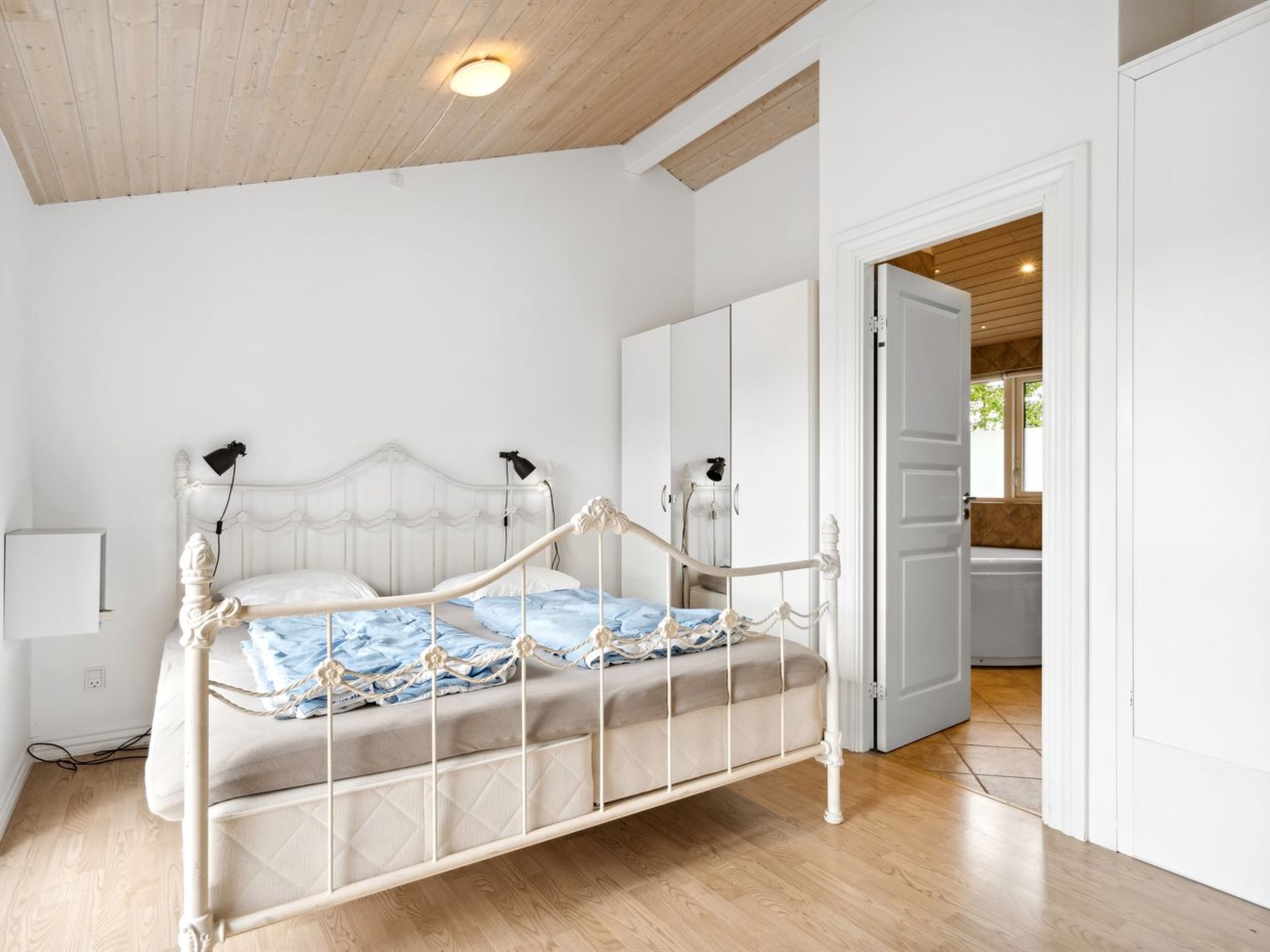A bedroom with a bed, wardrobe, and a view of the bathroom.