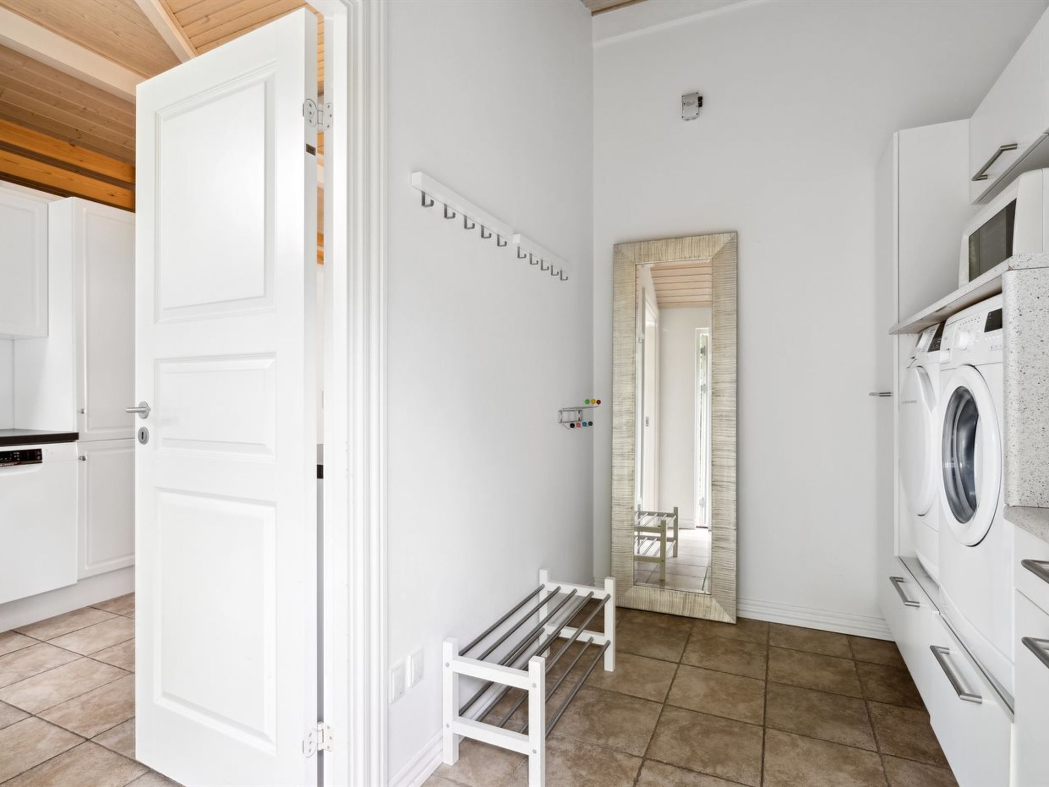 A laundry room with a washing machine, a drying rack, and a mirror on the wall.