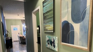A hallway with wooden flooring, green walls, and framed artwork. - Charming 1920’s shotgun in southern Indiana, minutes from downtown Louisville  (New Albany)