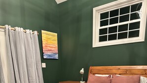 A bedroom with a wooden bed, a nightstand, a lamp, and a window. - Charming 1920’s shotgun in southern Indiana, minutes from downtown Louisville  (New Albany)
