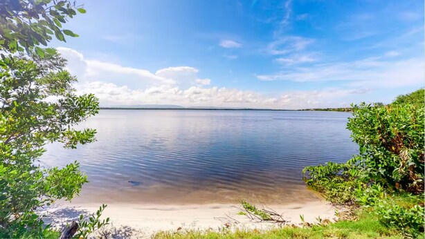 A calm lake with clear skies and distant land. - Lion Fish Retreat (Placencia)