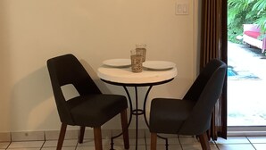A dining area with a round table, two chairs, and a framed picture on the wall. - Uptown quiet cottage close to beaches, restaurant & shopping.  (Key West)