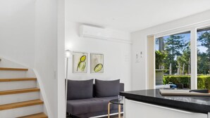 Una cocina moderna con encimera negra, sofá gris y una escalera con escalones de madera.