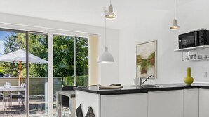Una cocina moderna con una isla grande, un comedor con puerta de vidrio al exterior y vistas al follaje.