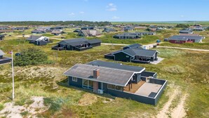 Une maison moderne dotée d’une grande terrasse et d’un intérieur spacieux, située dans un cadre rural.