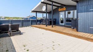 Un espace extérieur abrité, aménagé avec des tables et des chaises, une terrasse en bois et une enseigne indiquant qu’il s’agit d’un restaurant ou d’un café.