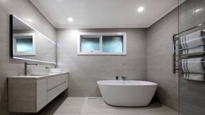 Un baño moderno con una bañera independiente, un tocador con espejo y un perchero para toallas.
