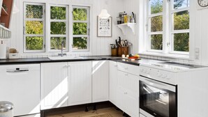 A modern kitchen with white cabinetry, a black countertop, and a built-in oven.