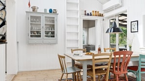A dining area with a wooden table and chairs, a cabinet with glass doors, and a patterned rug.