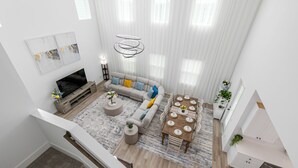 A modern living room with a sofa, coffee table, and dining table, a TV, and a staircase.