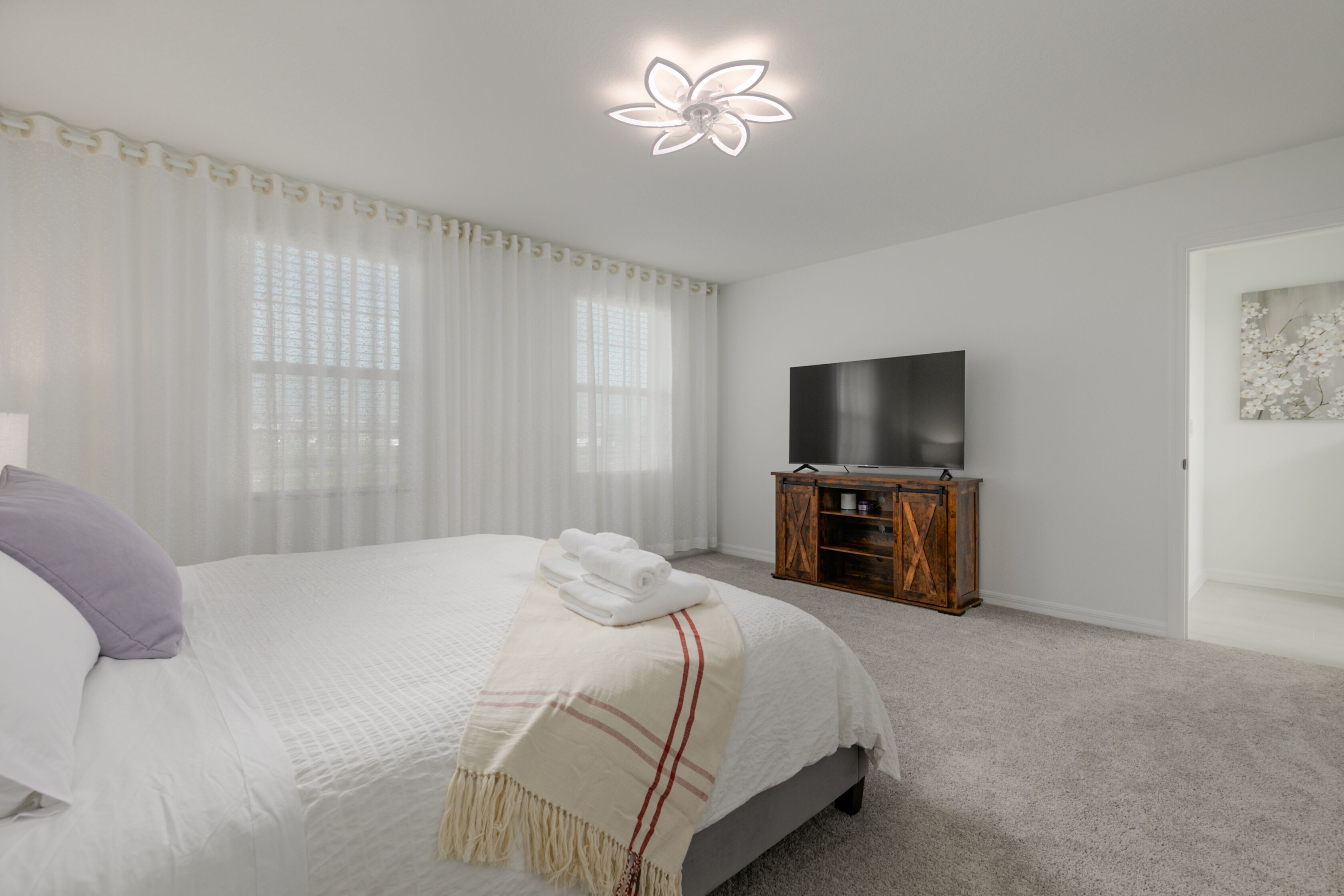 Una camera da letto con un letto, una TV su un mobile in legno e una lampada a soffitto.