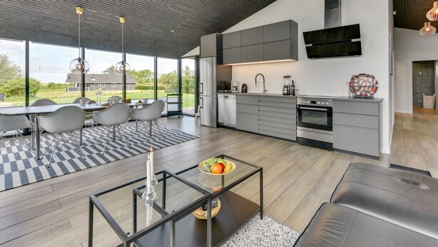 Une cuisine moderne dotée d’un grand îlot central, d’un coin repas avec un sol à carreaux et d’une vue sur l’extérieur.