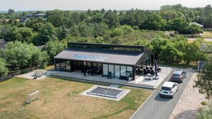 Un bâtiment moderne doté d’une façade en verre, d’une terrasse et d’un espace de stationnement.