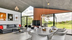 Un salon moderne avec une grande table à manger, des chaises blanches, un canapé et des œuvres d’art accrochées aux murs.