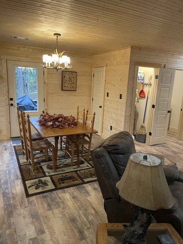 A cozy room with a wooden dining table, a leather couch, and a lamp. - Pickwick cabin near stateline boat ramp. 2 bed 2 full bath. Boat storage (Counce)