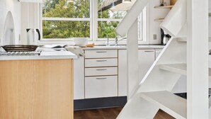 A modern kitchen with white cabinetry, a central island, and a view of greenery outside. - "Andrine" - 700m from the sea by Interhome (Henne)