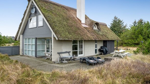 A house with a thatched roof, large windows, and a patio area with outdoor furniture. - "Andrine" - 700m from the sea by Interhome (Henne)