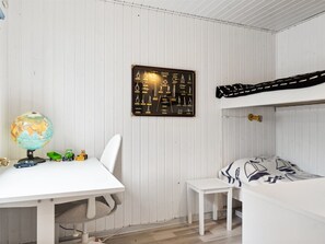 A child's bedroom with a bunk bed, a desk with toys, a globe, and a wall-mounted display of various items.
