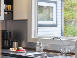 Una cocina con ventanal, un fregadero y varios utensilios sobre la encimera.