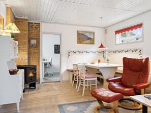 Una sala de estar acogedora con chimenea, un comedor con mesa y sillas, y un sillón de cuero rojo.