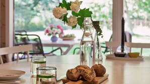 A dining table with a bottle, glasses, and bread on a wooden board. - "Judyta" - 250m to the fjord by Interhome (Nykøbing Sj)