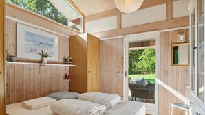 A bedroom with a large bed, wooden walls, a window, and a view of the outdoors. - "Judyta" - 250m to the fjord by Interhome (Nykøbing Sj)