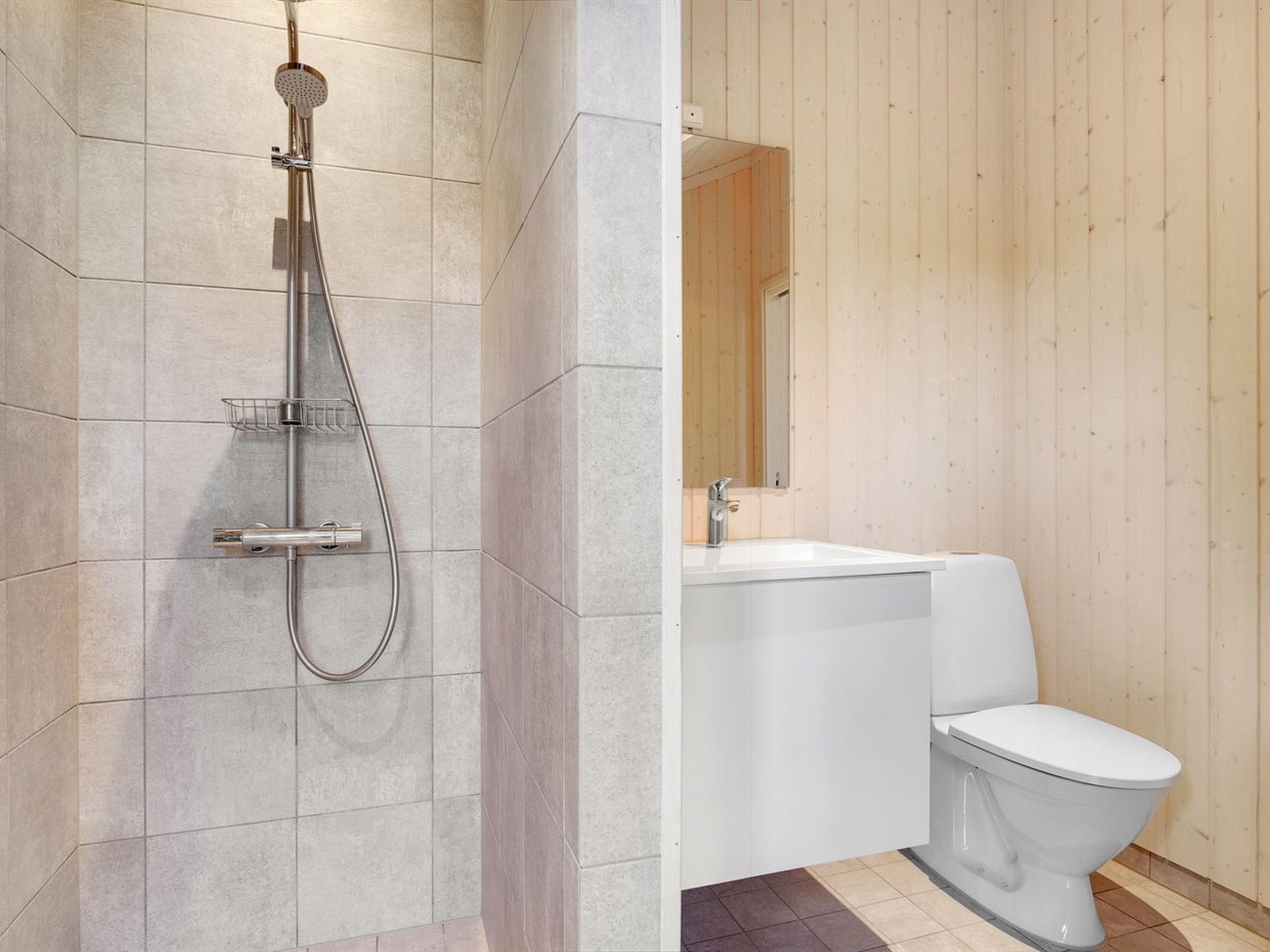 A modern bathroom with a shower, sink, and toilet.