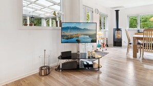 A spacious living room with a large TV, a fireplace, and a dining area with wooden furniture.