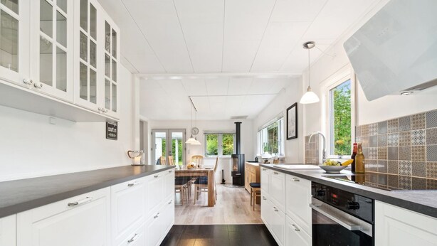 A modern kitchen with white cabinets, a black countertop, and a large window providing natural light.
