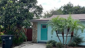 A house with a turquoise door, a stone exterior, and a front yard with palm trees. - Perfect 2/1 beach duplex apartment in the heart of STA beach (St. Augustine)