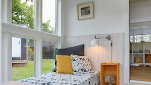 A bedroom with a bed, a bedside table with a lamp, a picture on the wall, and a view of the outdoors. - "Anemette" - 100m from the sea by Interhome (Nexø)
